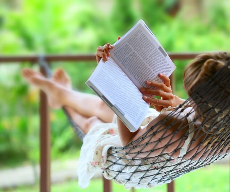 woman reading a book in a hammock