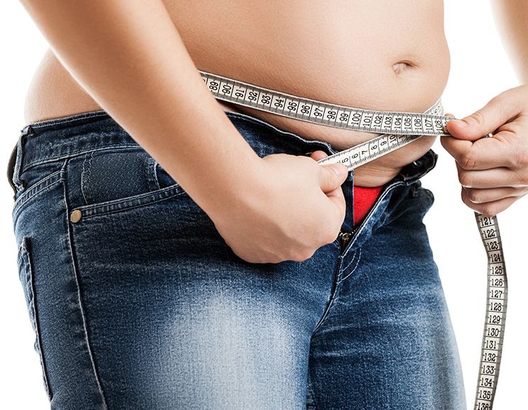 overweight woman measuring her waist
