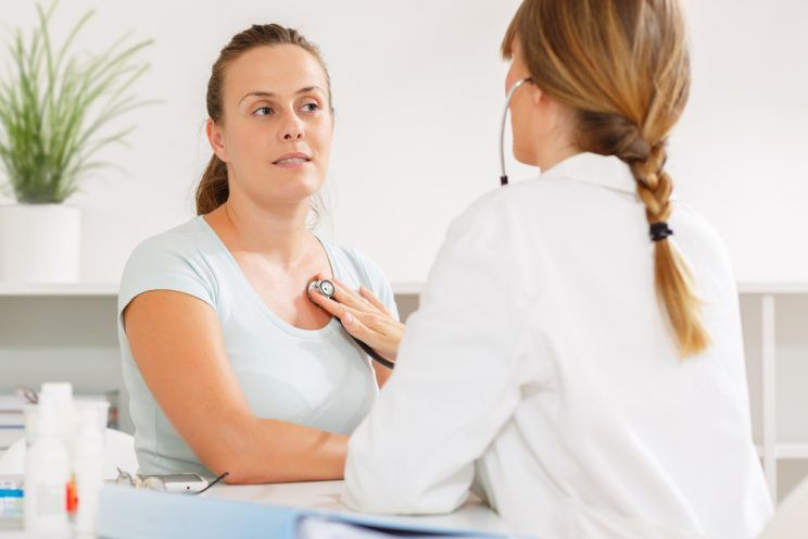 Doctor listening to a womans heart with a stethoscope