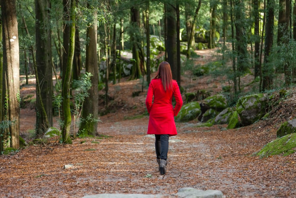 Young woman walking away alone on a forest