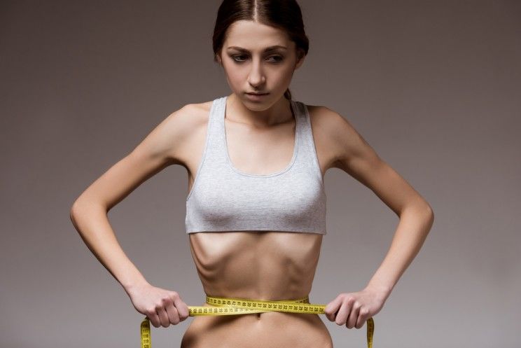 thin girl measuring her tiny waist