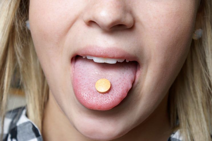 A young girl takes a vitamin c chewable tablet