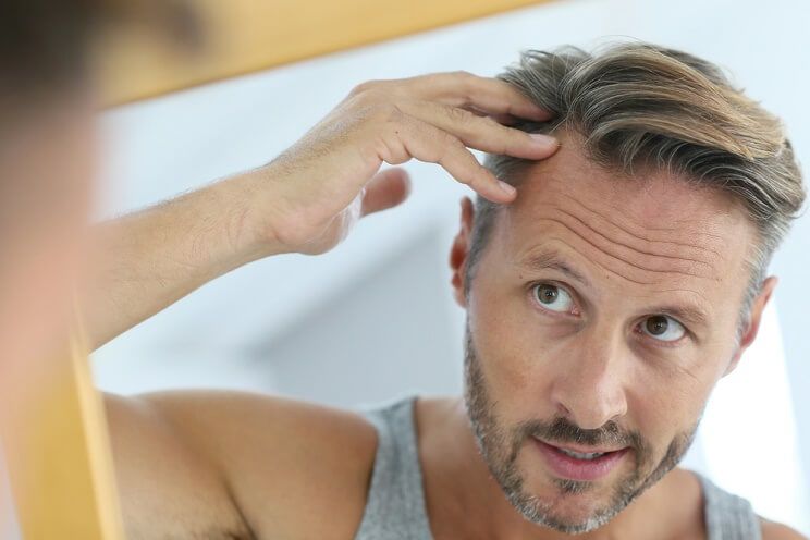 man looking at hair in mirror