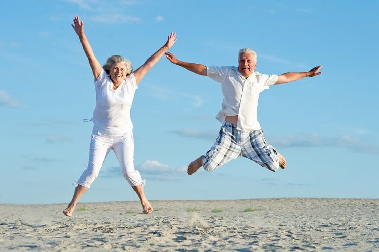 older couple jumping on beach