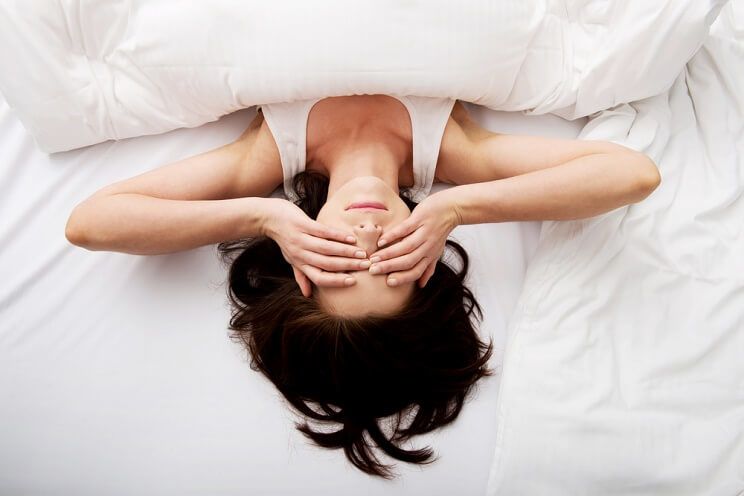 woman rubbing her eyes in bed