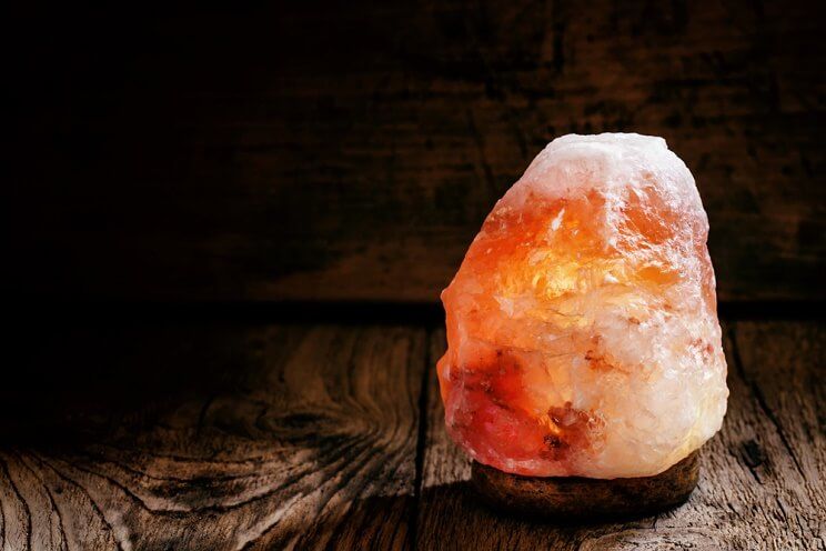 A lit Himalayan salt lamp on a wooden table