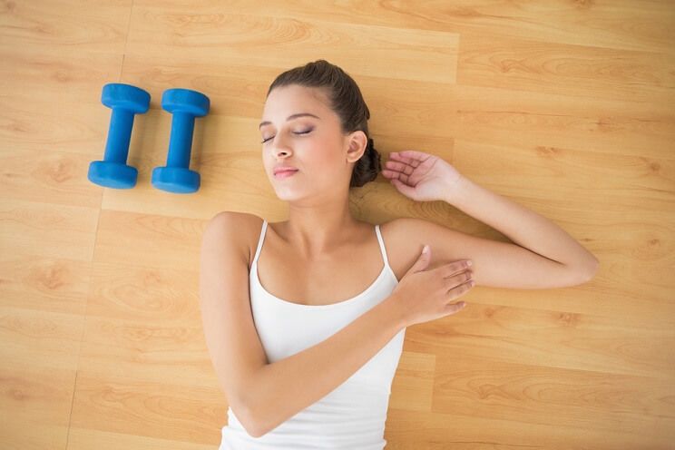 athletic woman sleeping next to barbells