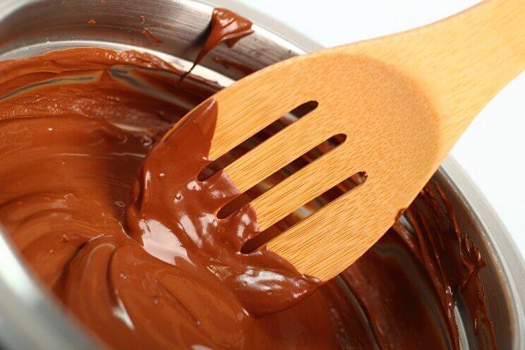 a wooden spoon stirring melted chocolate