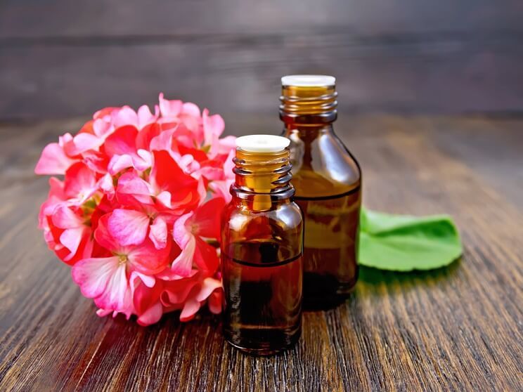 bottles of geranium oil with geranium flower