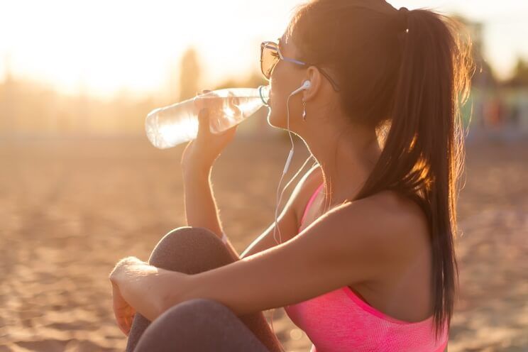 woman hydrating on a beach