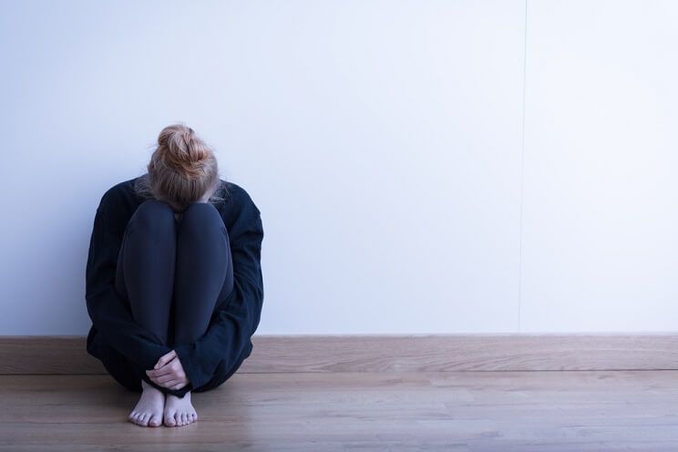 depressed woman sitting against a wall