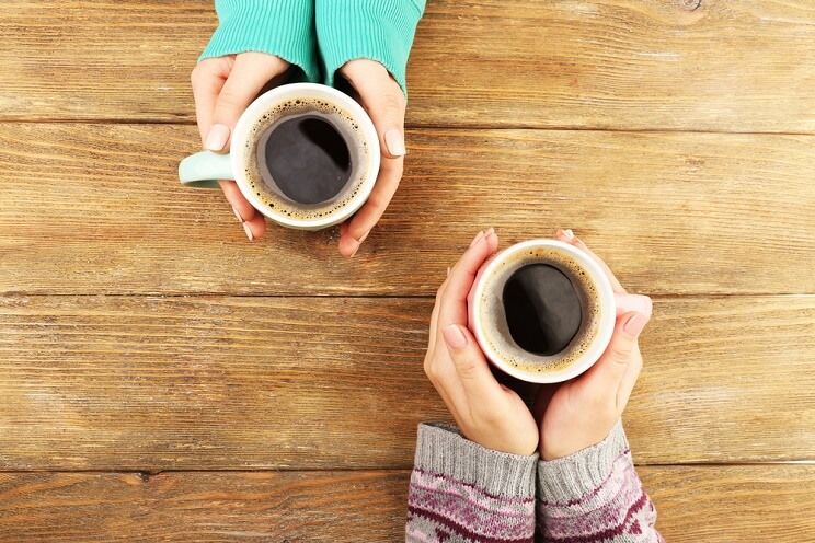 women holding coffee cups on a wooden table