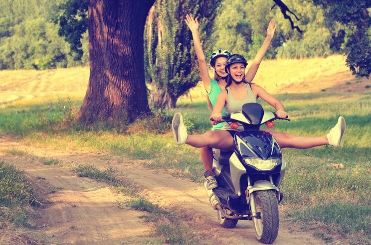 women on a bike outside and laughing for stress management