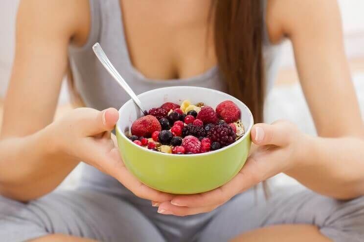 woman eating bowl of berries