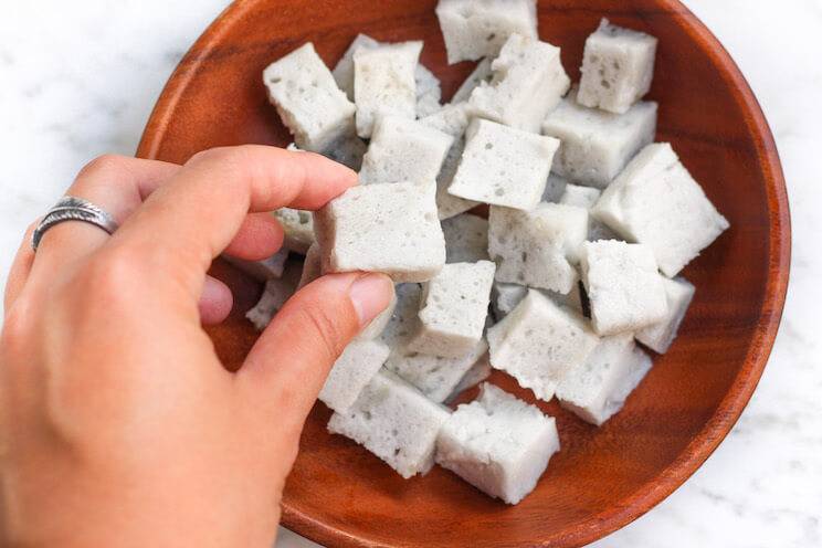 fingers picking up homemade collagen marshmallows in a bowl