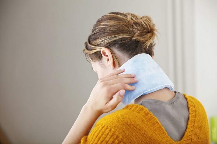 woman using hot pad on neck