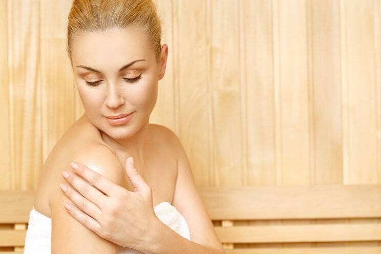 woman putting oil on skin in sauna