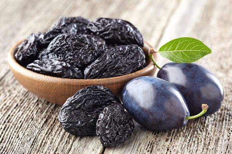 prunes in a bowl with plums alongside