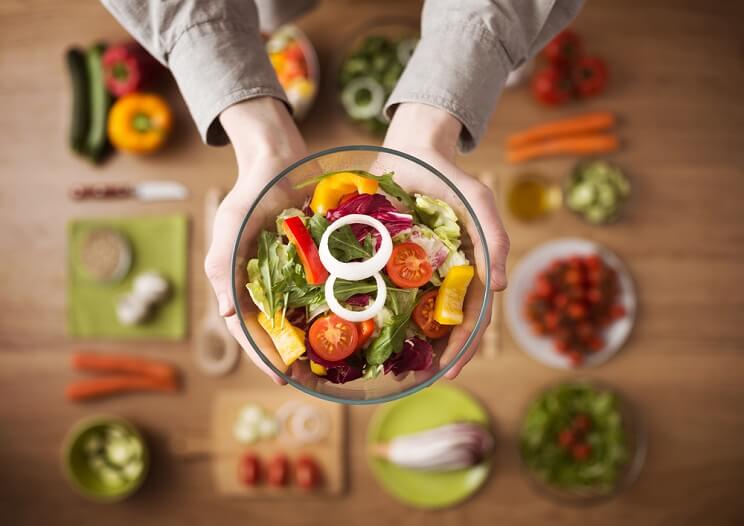 hands holding a bowl of salad