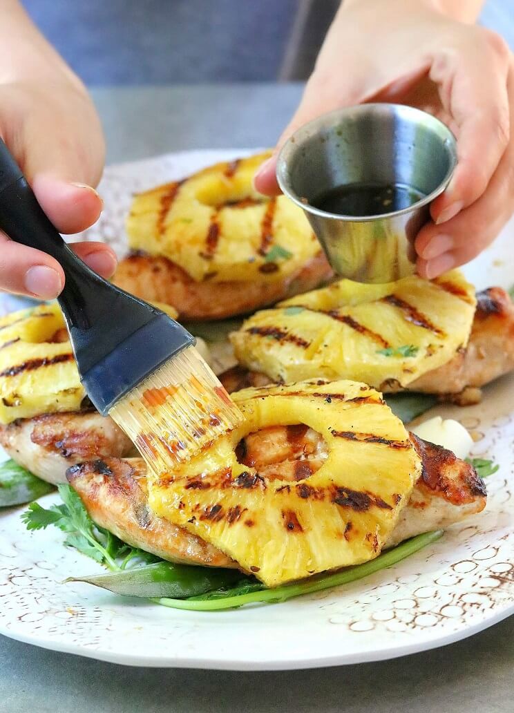 brushing pineapple slices with marinade