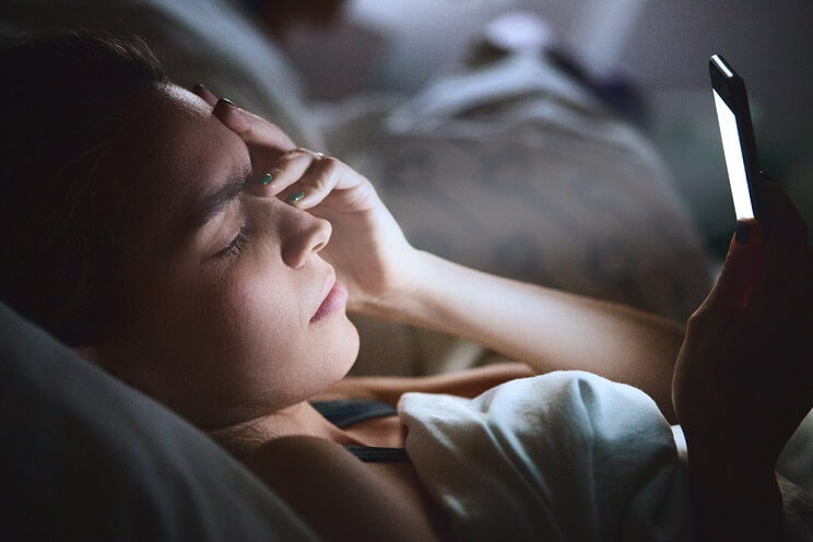 anxious girl with cell phone in bed