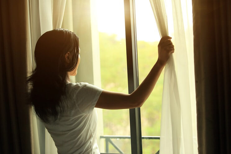 woman opening curtains in the morning