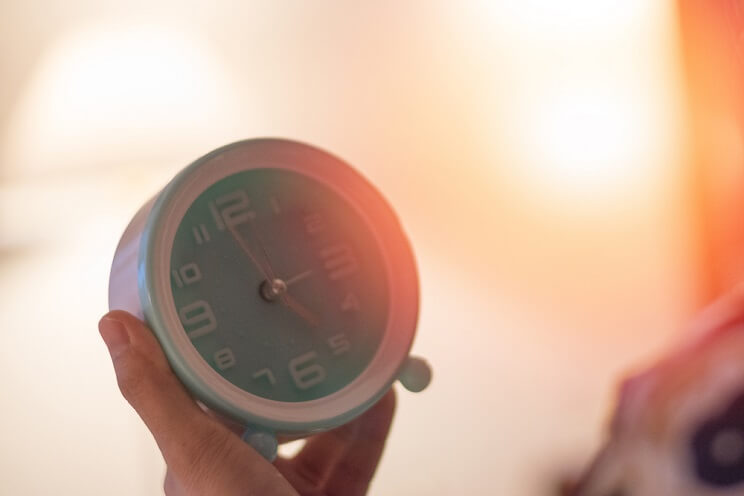 hand holding alarm clock in sunlight