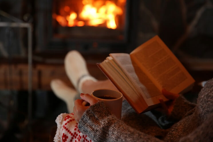 reading by the fireplace with a cup of tea