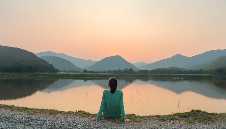 woman looking out onto serene lake