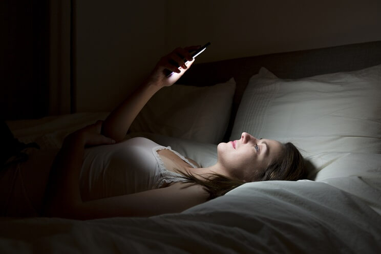 woman looking at phone in bed