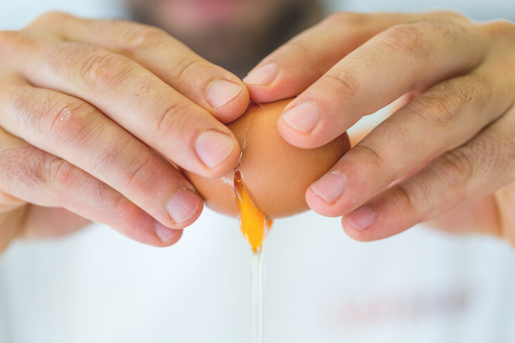 hands cracking an egg open