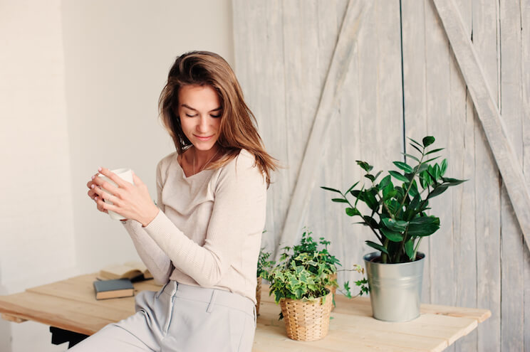 woman sitting on a table next to plants indoors