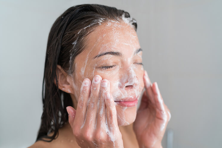woman cleaning her face with soap and water