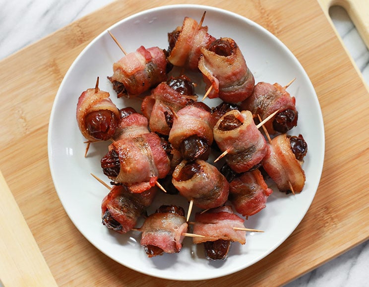 Savory bacon wraps around sweet dates and roasted in the oven for a classic appetizer on a stick.