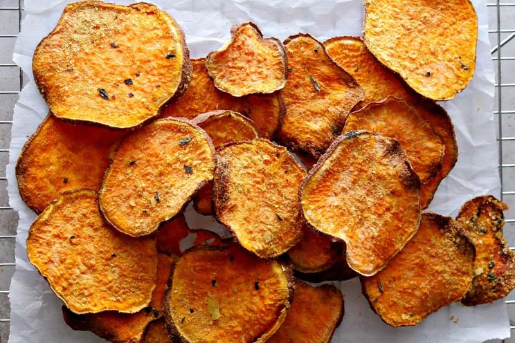 Craving potato chips? These sweet potato crisps are coated in cheesy nutritional yeast and dried herbs for flavorful munchies with no frying necessary.