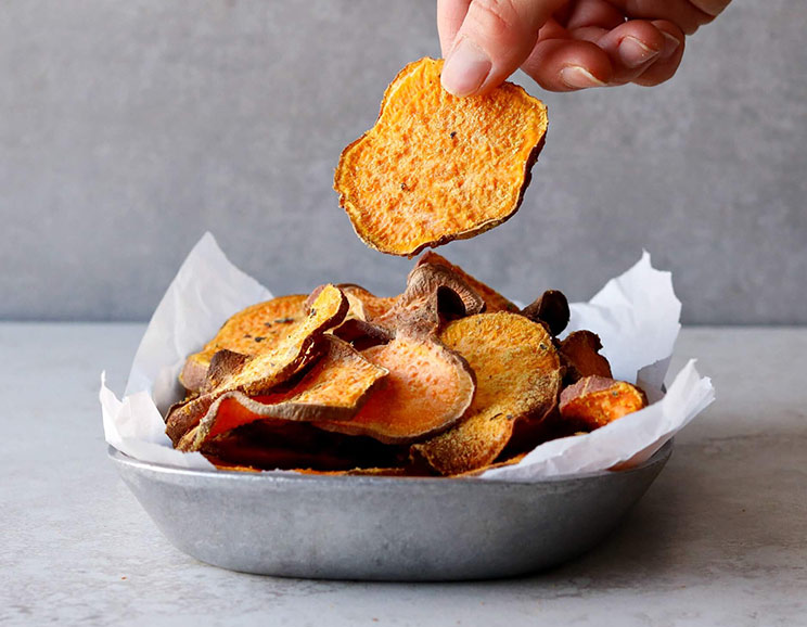 Craving potato chips? These sweet potato crisps are coated in cheesy nutritional yeast and dried herbs for flavorful munchies with no frying necessary.