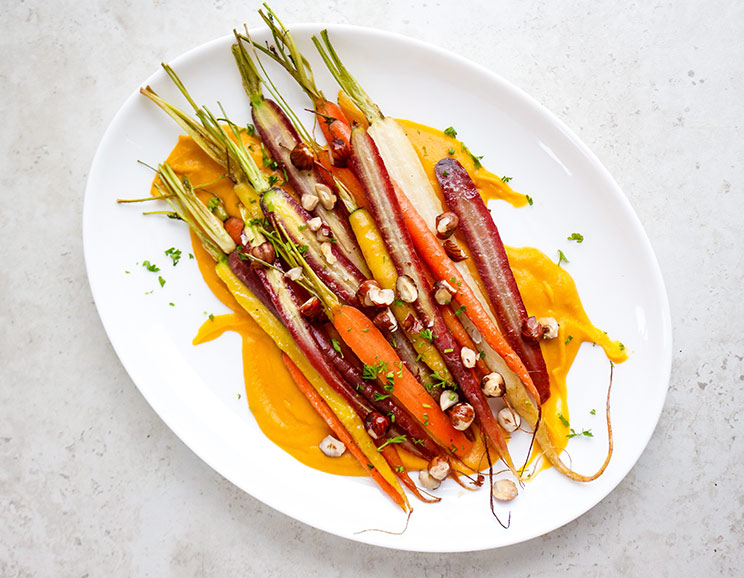 Honey-roasted rainbow carrots are served on top of a creamy sweet potato purée for an easy, elegant veggie dish. This side dish is anything but boring!