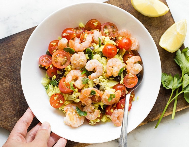 Season cauliflower couscous with fresh Mediterranean flavors like olives, capers, lemon, and parsley, and top with garlicky shrimp.
