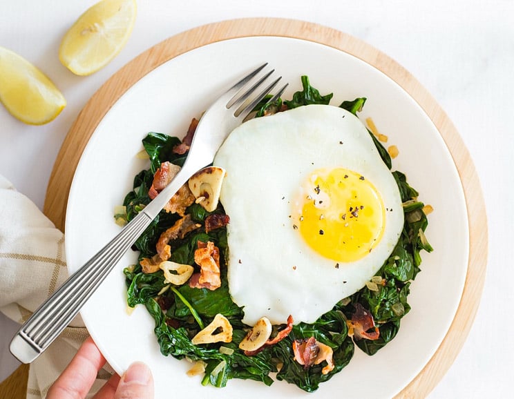 Fresh spinach gets tossed in hot, garlicky bacon and shallots for a savory side dish you’ll love. Bacon and greens are our favorite breakfast combo!