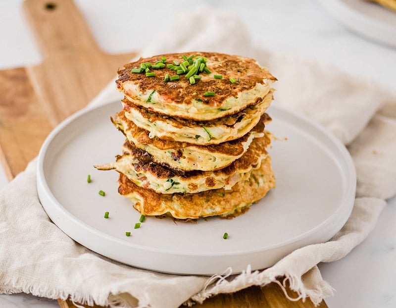 Start your morning with savory zucchini pancakes filled with bites of crunchy bacon and fresh chives! They're packed with protein, fiber and healthy fat.